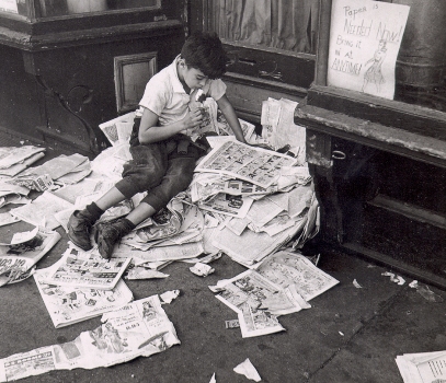 Niño leyendo tiras cómicas en una calle de Nueva York, de André Kertész
